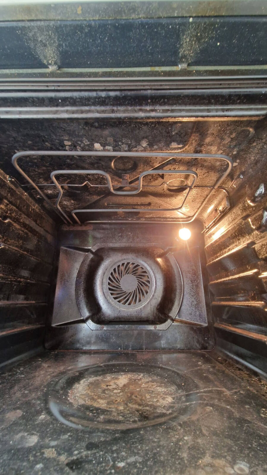 Inside of a fan oven before cleaning, coated in burnt-on carbon and grease